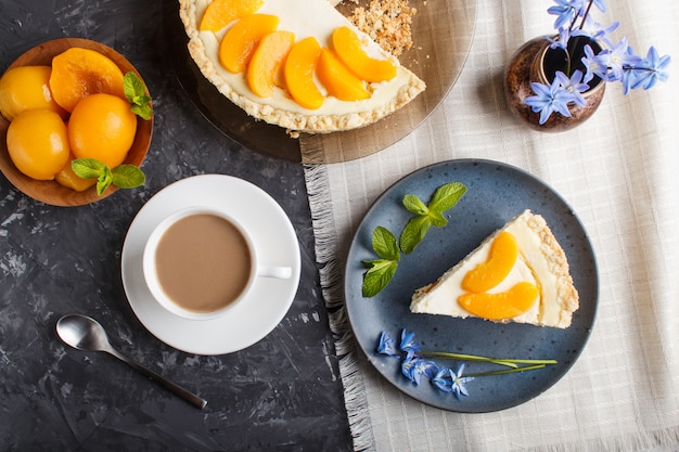 Um pedaço de bolo de pêssego em uma placa de cerâmica azul com flores azuis e uma xícara de café em preto