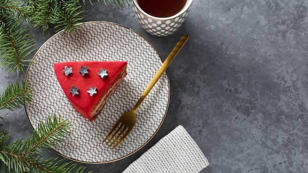 Um pedaço de bolo vermelho e uma xícara de chá em fundo cinza Decoração de Natal