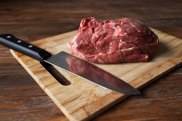 Foto um pedaço de carne fresca e uma faca em uma tábua de corte sala para texto foto de alta qualidade