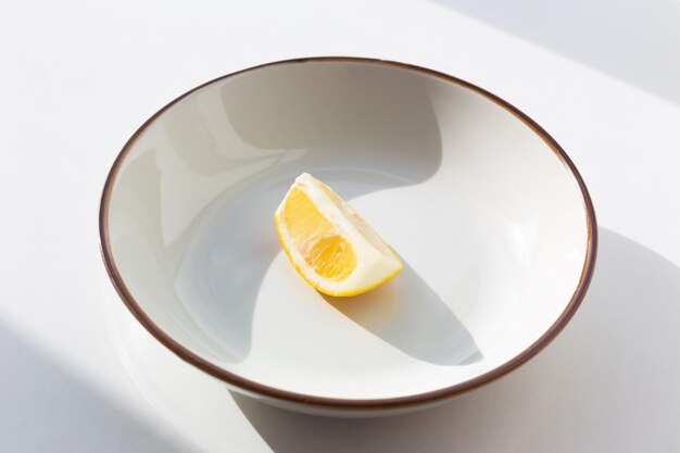 Um pedaço de limão em um prato branco sobre um fundo branco