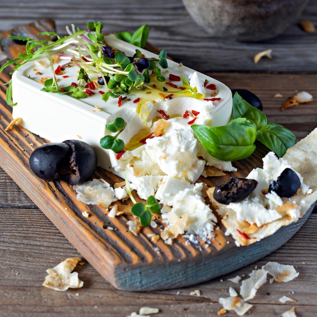 Um pedaço de painel de queijo feta fresco com azeitonas, ervas, especiarias e fatias de pão achatado