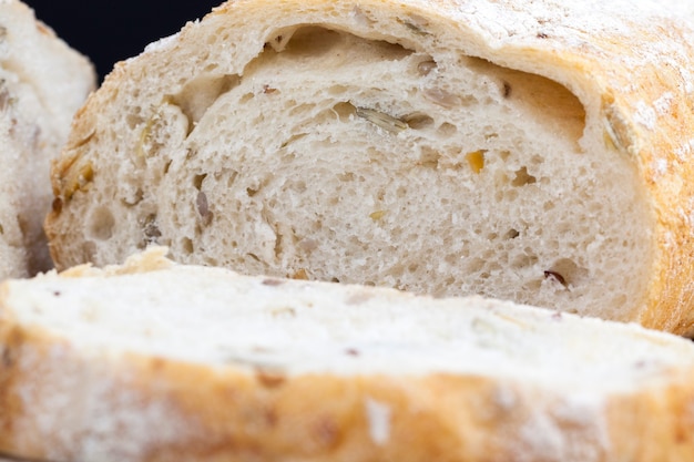 Um pedaço de pão de trigo fresco na mesa durante o cozimento, pão fresco macio com sementes de abóbora e sementes de linho