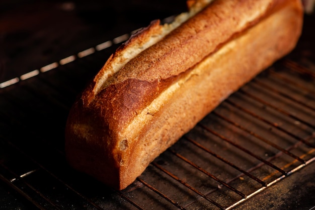 Um pedaço de pão francês em forma oblonga sobre um fundo escuro