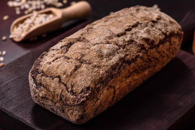 Um pedaço de pão integral com grãos de cereais em uma tábua de madeira