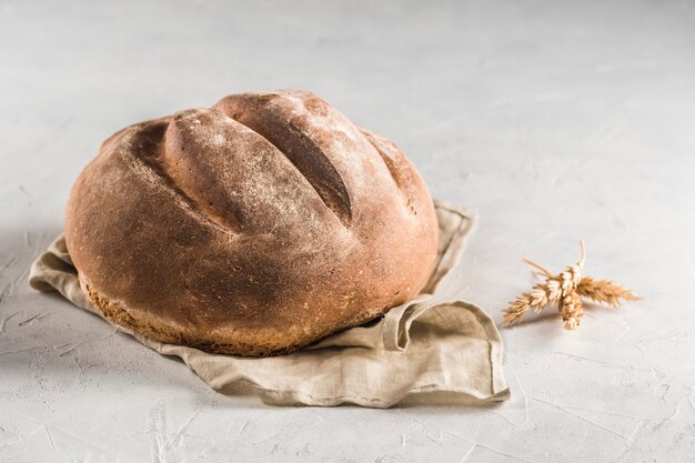Um pedaço de pão redondo em um guardanapo de linho cinza sobre um fundo claro.