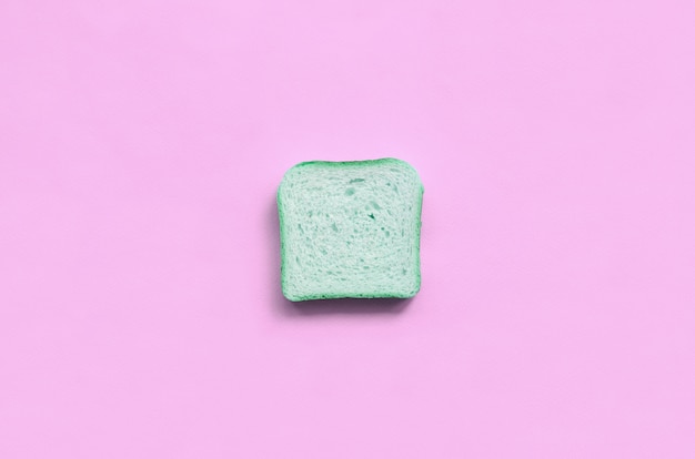 Um pedaço de pão verde encontra-se na textura de papel de cor rosa pastel moda