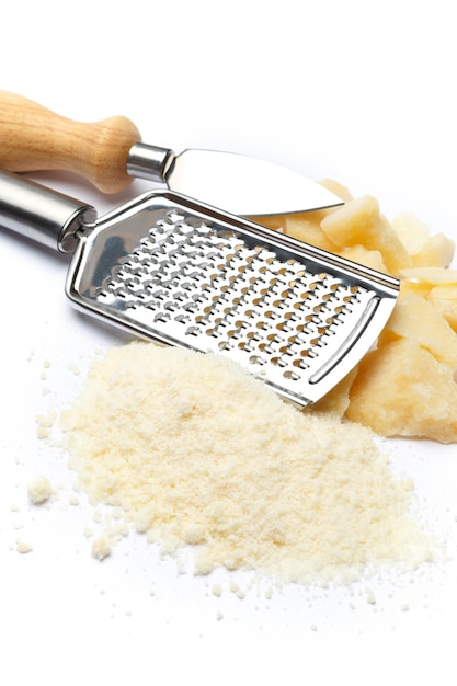 Um pedaço de queijo parmesão e ralado na mesa branca