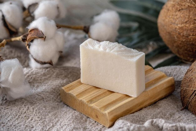 Um pedaço de sabão natural branco feito à mão em uma saboneteira de madeira