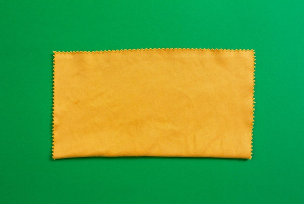 Um pedaço de tecido amarelo com uma borda costurada em um fundo verde.