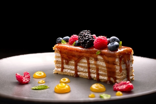 Um pedaço de torta, bolo de mel com frutas frescas, hortelã e caramelo