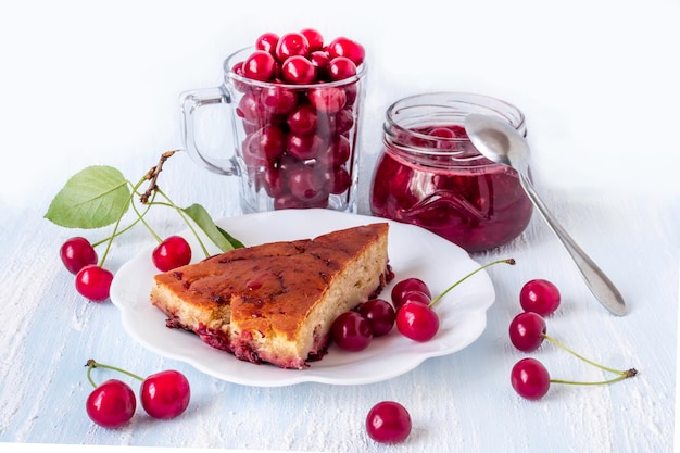 Um pedaço de torta de cereja em um prato com cerejas ao fundo