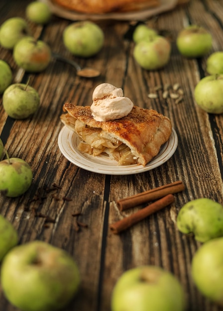 Um pedaço de torta de maçã caseira com uma bola de sorvete em um prato e os ingredientes para isso