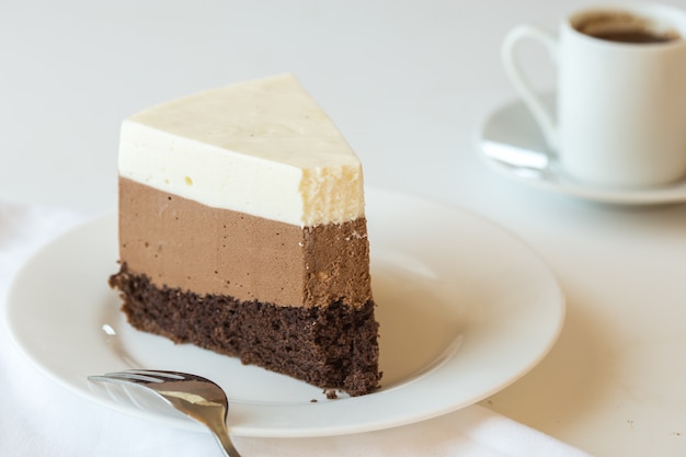 Um pedaço de um bolo de mousse "três chocolate" polvilhado com chocolate ralado e doces decorados