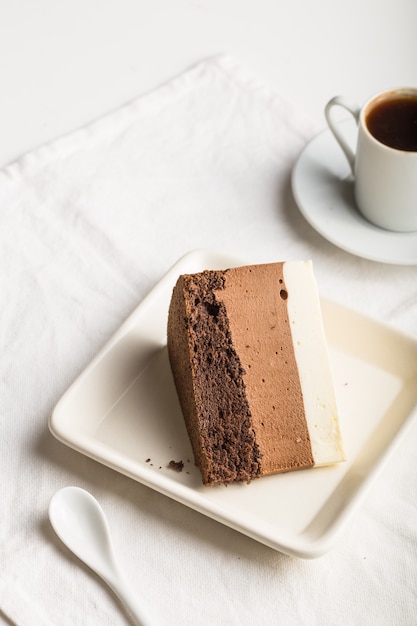 Um pedaço de um bolo de mousse "três chocolate" polvilhado com chocolate ralado e doces decorados