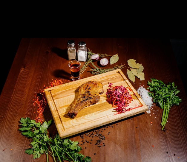 Um pedaço suculento de carne frita encontra-se em uma tábua contra uma mesa de madeira.