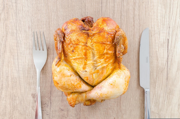 Foto um peito de frango é colocado em uma mesa de madeira.