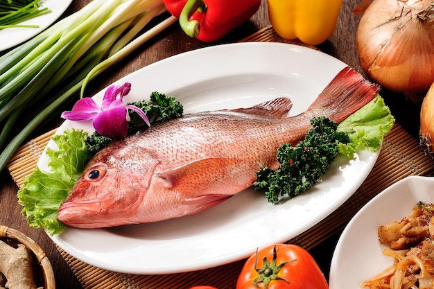 um peixe está em um prato com legumes e frutas