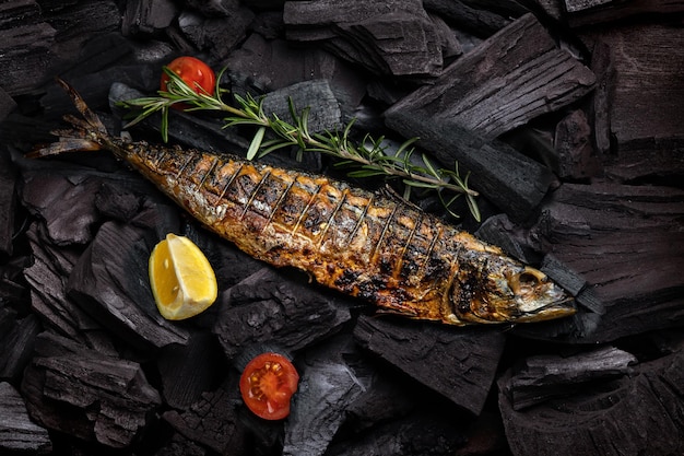 Um peixe grelhado fica em uma grelha com limão e tomate.