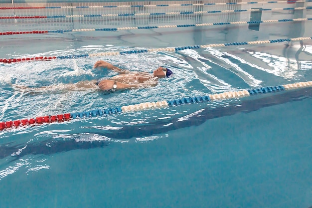 Um pensionista de 70 anos está descansando nadando se recuperando na piscina com água clara e azul no hotel