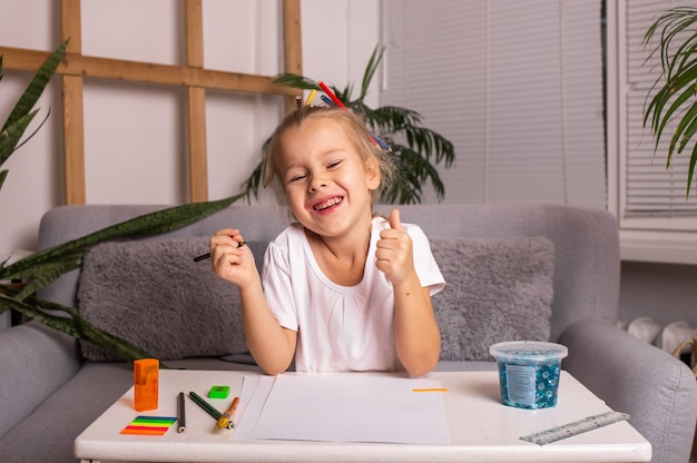 Um pequeno artista está sentado a uma mesa com papel e lápis