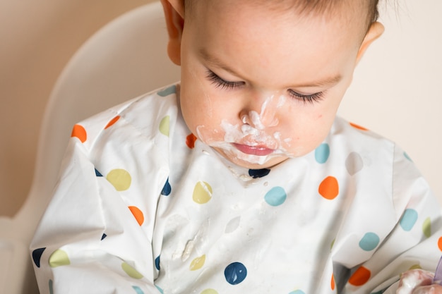 Um pequeno bebê comendo seu jantar e fazendo uma bagunça