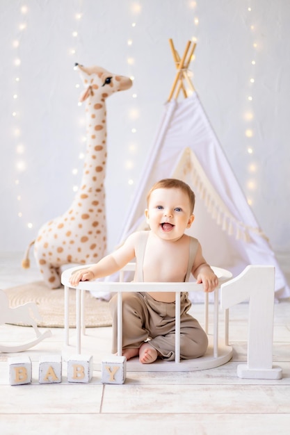 Um pequeno bebê sorridente brincando no berçário um quarto infantil aconchegante e brilhante o primeiro aniversário do bebê os adereços do primeiro ano para o feriado