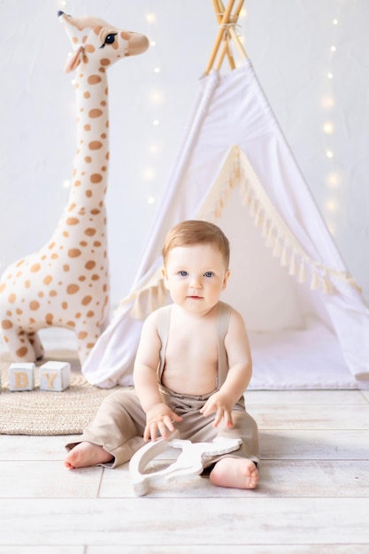 Um pequeno bebê sorridente brincando no berçário, um quarto infantil brilhante e aconchegante, têxteis naturais e brinquedos de madeira para o berçário