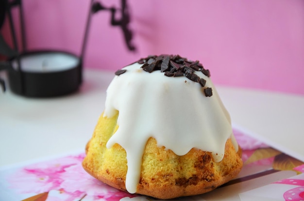 Um pequeno bolo com glacê branco e chocolate por cima.