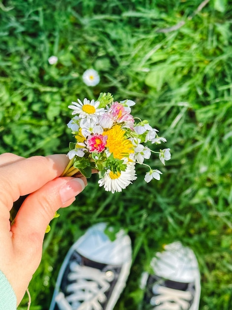 um pequeno buquê de flores silvestres nas mãos no contexto do rio