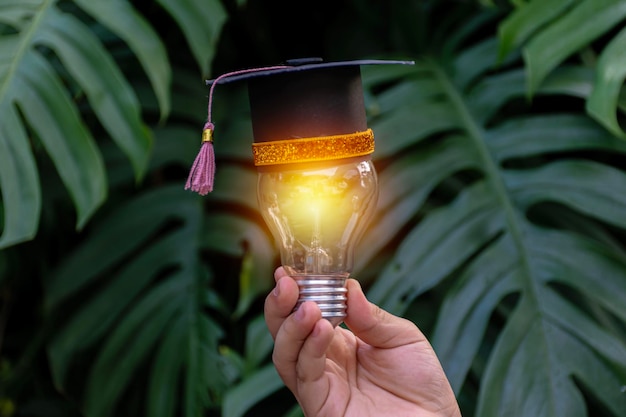 Foto um pequeno chapéu de formatura colocou uma lâmpada brilhante na mão de uma criança e um sentimento de felicidade no dia da formatura conceito de educação empresarial