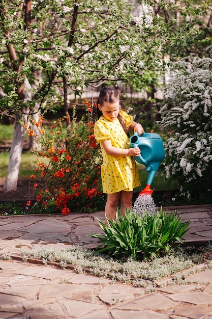 Um pequeno jardineiro está regando flores de um regador, uma menina está jardinando no quintal de uma casa.