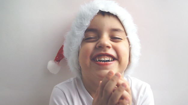 Um pequeno lindo menino sorridente com um chapéu de Papai Noel O conceito de Feliz Natal