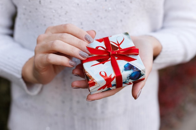 Um pequeno presente de Natal nas mãos de uma mulher, close-up