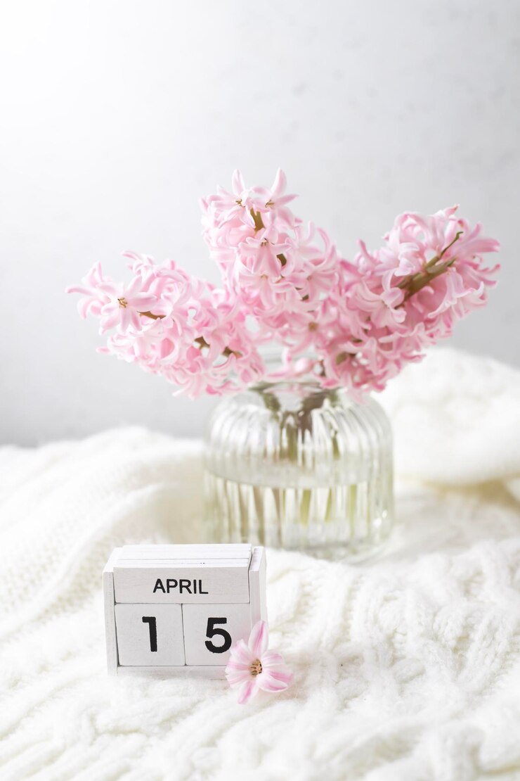 Foto um pequeno vaso com flores cor de rosa e uma data de 15 de abril.