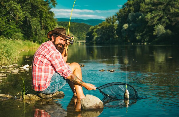 Um pescador apanhou um peixe. Um homem a pescar no rio.