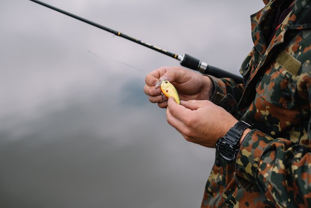 Um pescador com uma vara de pescar na margem do rio