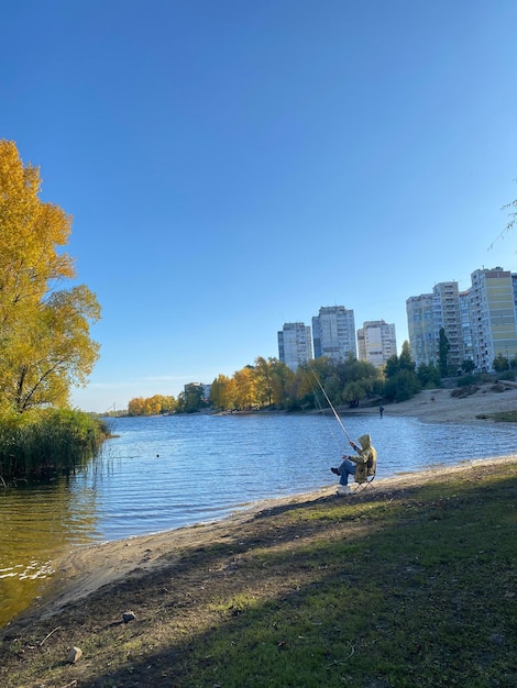 Foto um pescador com uma vara de pescar no contexto de uma paisagem de outono no rio