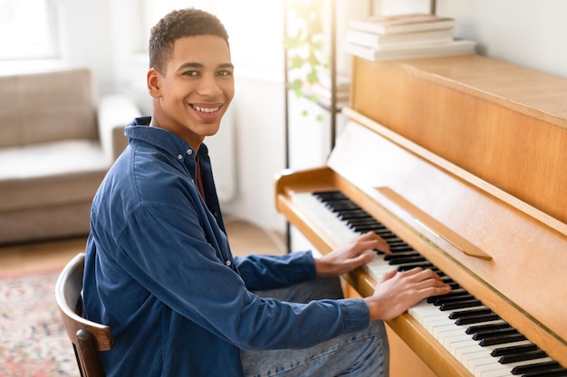 Um pianista negro sorridente a desfrutar de música em casa.