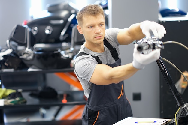 Foto um piloto masculino em uma garagem troca peças de uma motocicleta