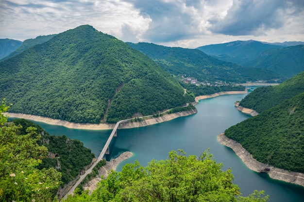 Um pitoresco lago turquesa pode ser visto do topo de uma montanha alta.