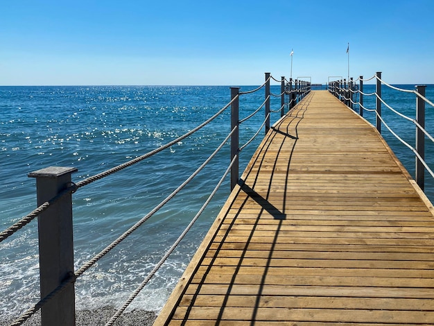 Um pontão longo de madeira um píer com uma grade de corda no mar na praia de férias em um paraíso