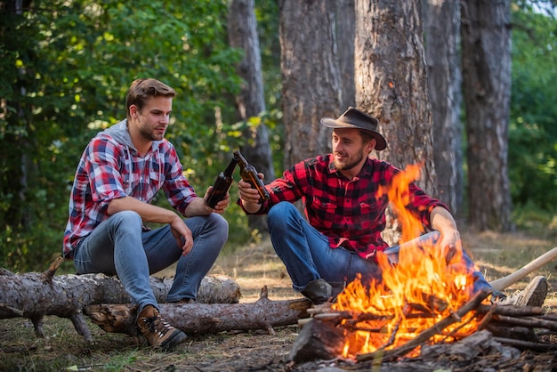 Um ponto de encontro. aventura de caminhada. piquenique no acampamento de turismo. irmãos de homens felizes. amigos relaxando no parque juntos. beber cerveja no piquenique. história de vida da fogueira. passem tempo livres juntos. família acampar.