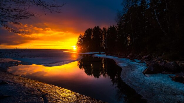 um pôr-do-sol é refletido na água e as árvores são refletidas na água