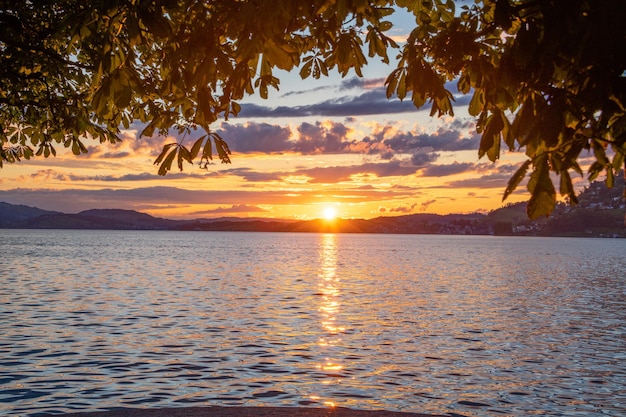 Um pôr do sol no lago, a borda superior é coberta por folhas