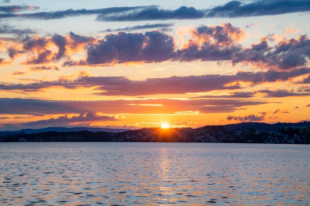 Um pôr do sol no lago com nuvens vermelhas roxas