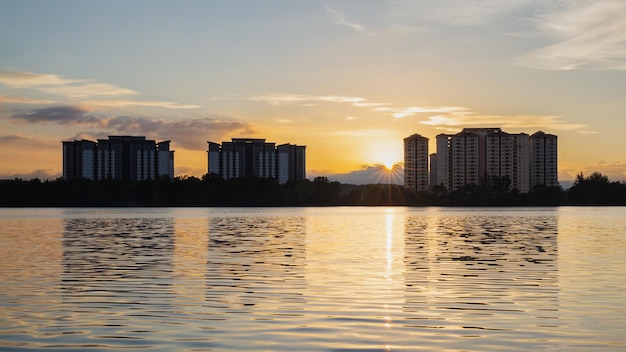 Um pôr do sol sobre a água com um prédio ao fundo