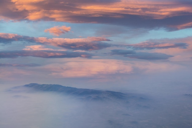 Um pôr do sol sobre as montanhas com um céu nublado ao fundo