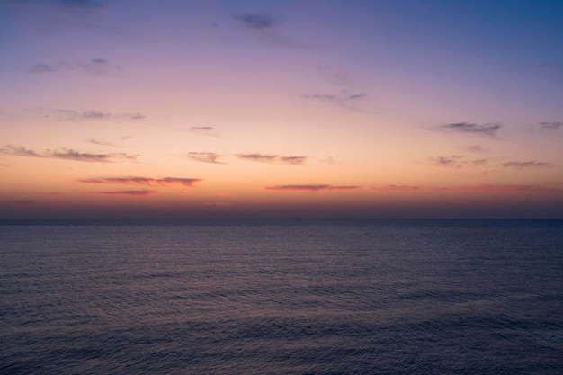 Um pôr do sol sobre o mar com um céu roxo e algumas nuvens