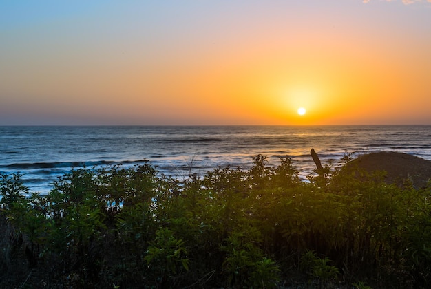 Um pôr do sol sobre o oceano com o sol se pondo atrás dele