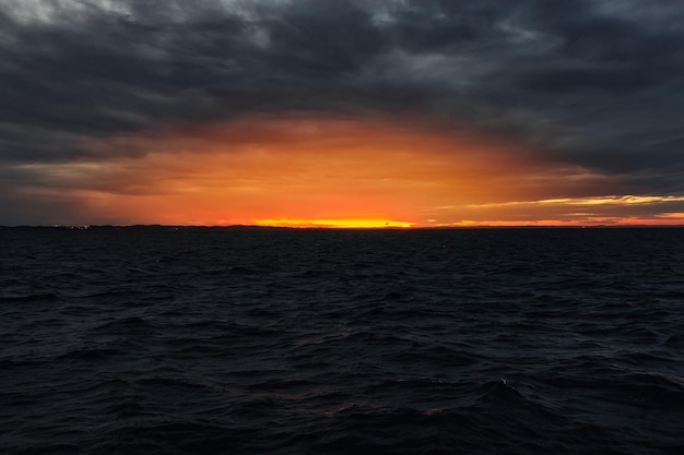 Um pôr do sol sobre o oceano com um céu escuro e nuvens